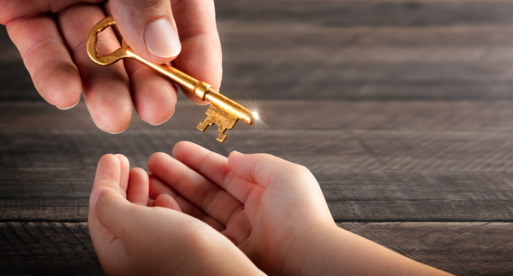 gold key being given to child hands