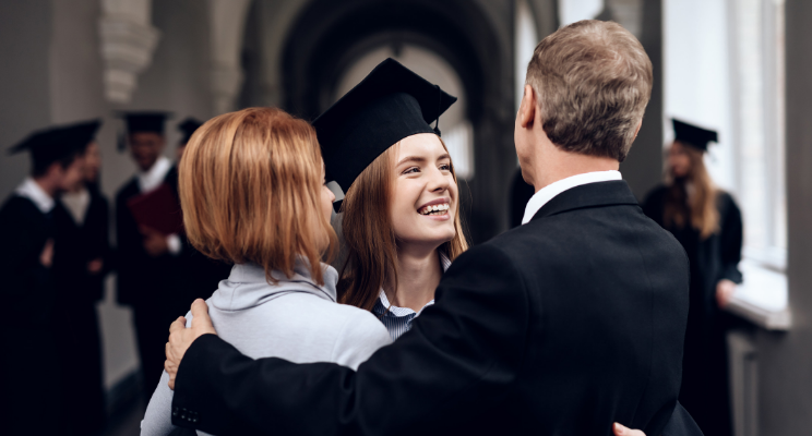 graduating student in embrace with man and woman